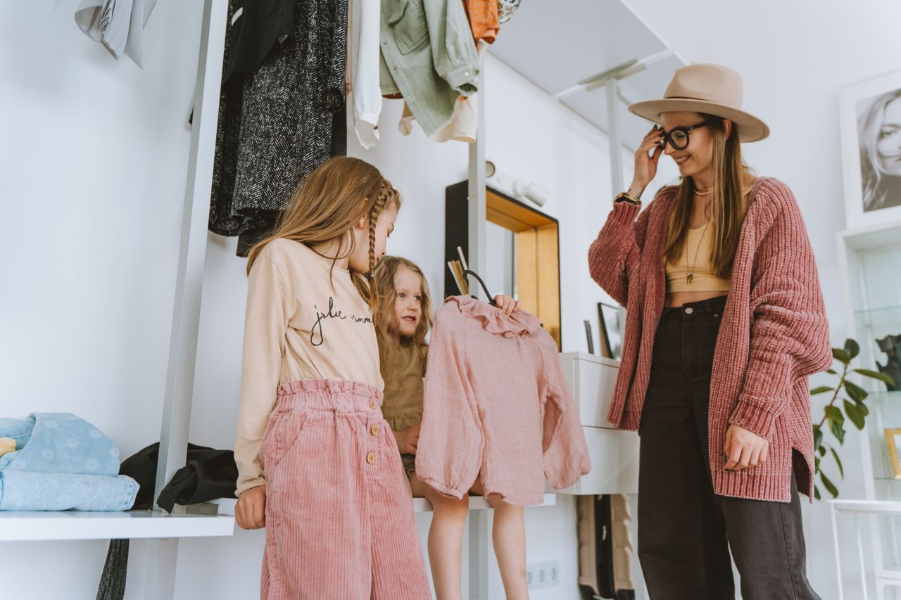 Crafting Captivating Headlines: Your awesome post title goes here A mother and her daughters choose outfits in a stylish, cozy home setting.